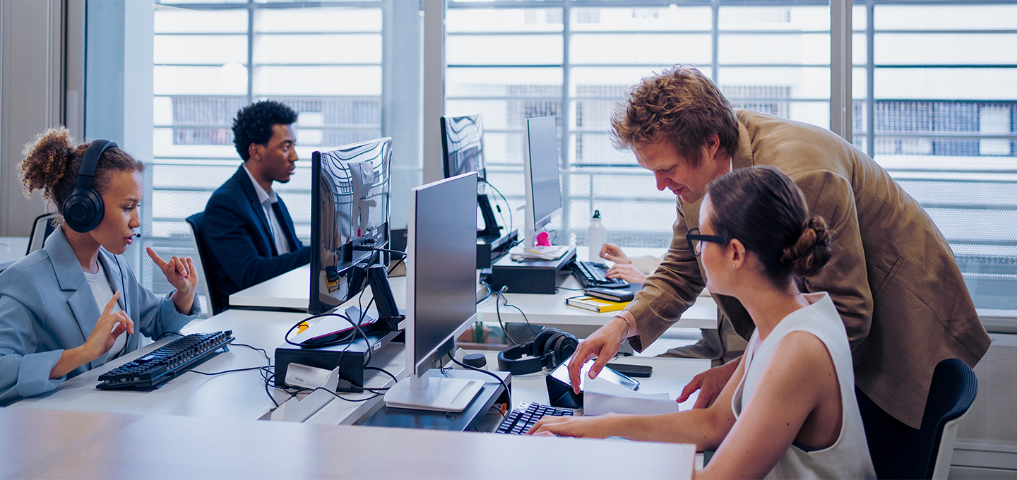 Team di professionisti che collabora in un ufficio moderno con postazioni informatiche